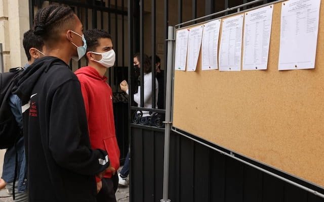 Jeunes portant des masques regardant des annonces d'emploi sur un tableau.