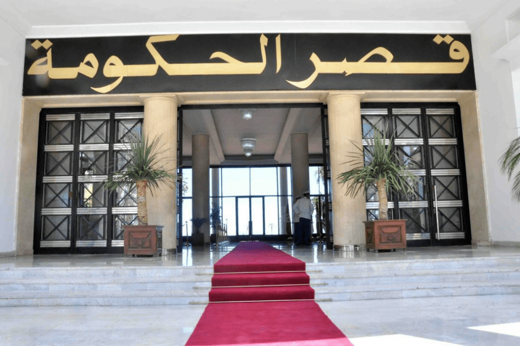 Entrée du siège du gouvernement avec tapis rouge et plantes décoratives.