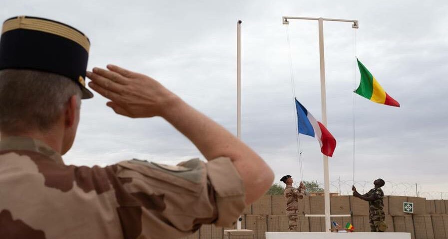 Cérémonie militaire avec drapeaux Soldat saluant lors d'une cérémonie avec drapeaux français et africains.