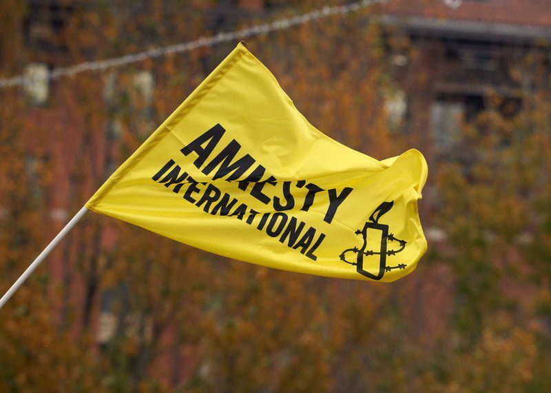 Drapeau jaune d'Amnesty International flottant dans le vent.
