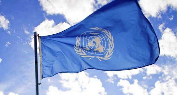 Drapeau de l'ONU flottant dans le ciel bleu avec nuages.