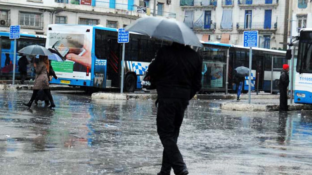 Personne sous un parapluie dans une rue inondée en Algérie.