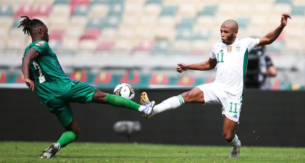 Joueur algérien et camerounais en duel lors d'un match de football.