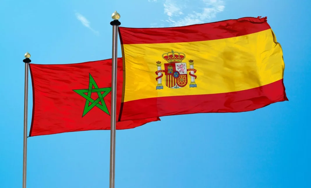 Drapeaux du Maroc et de l'Espagne flottant dans le ciel bleu.