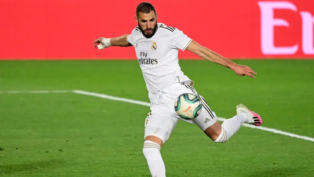 Karim Benzema en train de tirer le ballon sur le terrain de football.