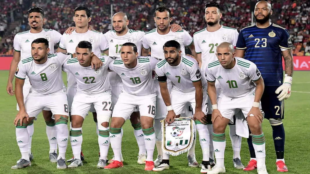 Groupe de joueurs de football algériens en tenue officielle sur le terrain.
