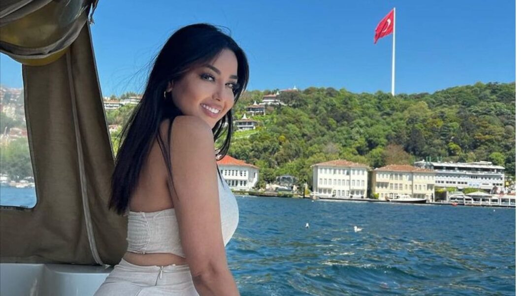 Yasmine Belkacem souriante en bateau avec vue sur la mer et la ville.