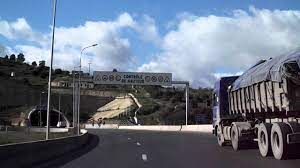 Autoroute en Algérie avec camions et panneaux de signalisation.
