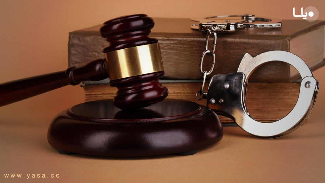 Juge, marteau, menottes et chaîne de prison sur une table.