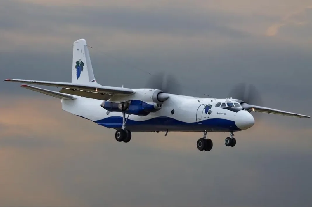 Avion de ligne blanc avec logo vert en vol dans le ciel nuageux.