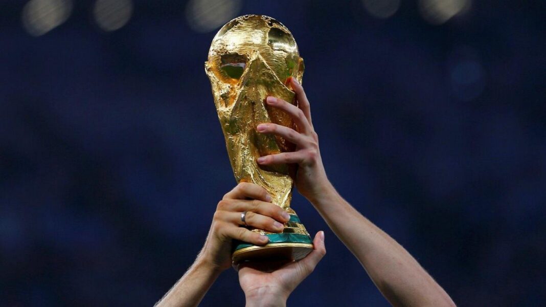 Main tenant la coupe du monde en or lors d'une cérémonie.