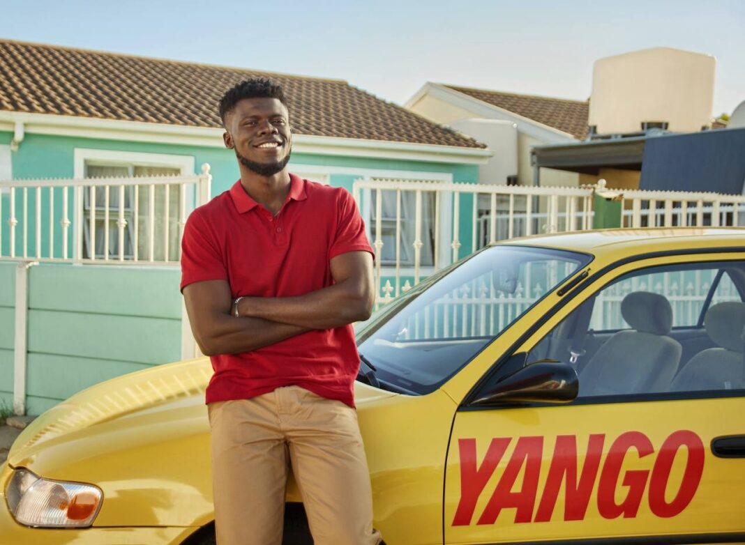 Homme souriant à côté d'une voiture Yango en Algérie.