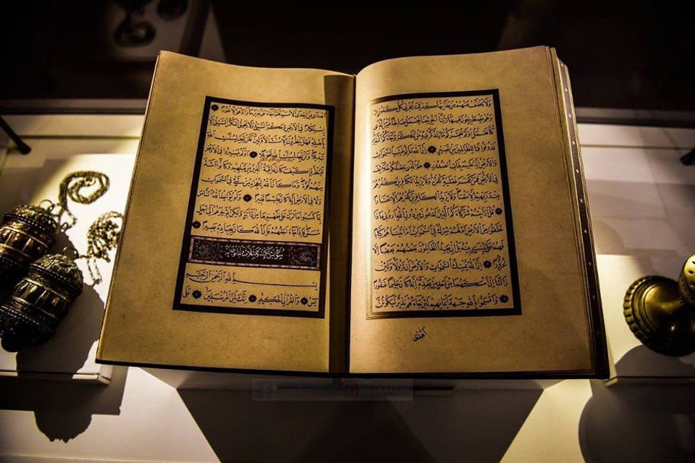Page du Coran ouverte avec calligraphie arabe ancienne.