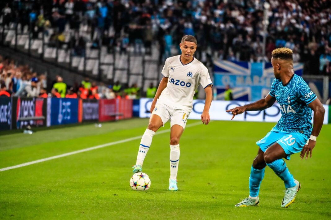 Harit en action lors d'un match de football avec un adversaire.