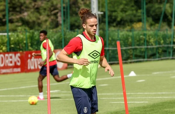 Joueur de football en entraînement avec des cônes sur le terrain.