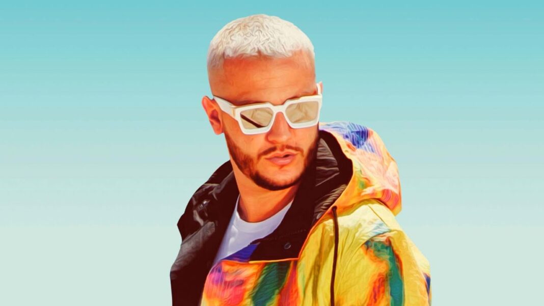 DJ Snake portant des lunettes blanches et un manteau coloré.
