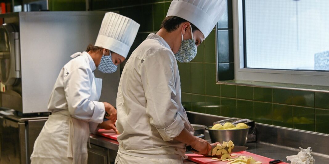 Cuisiniers en formation en cuisine Cuisiniers en formation portant des masques en cuisine professionnelle.