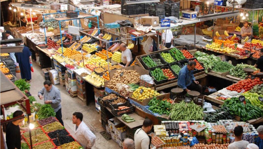 Vendeurs et clients dans un marché coloré en Algérie.