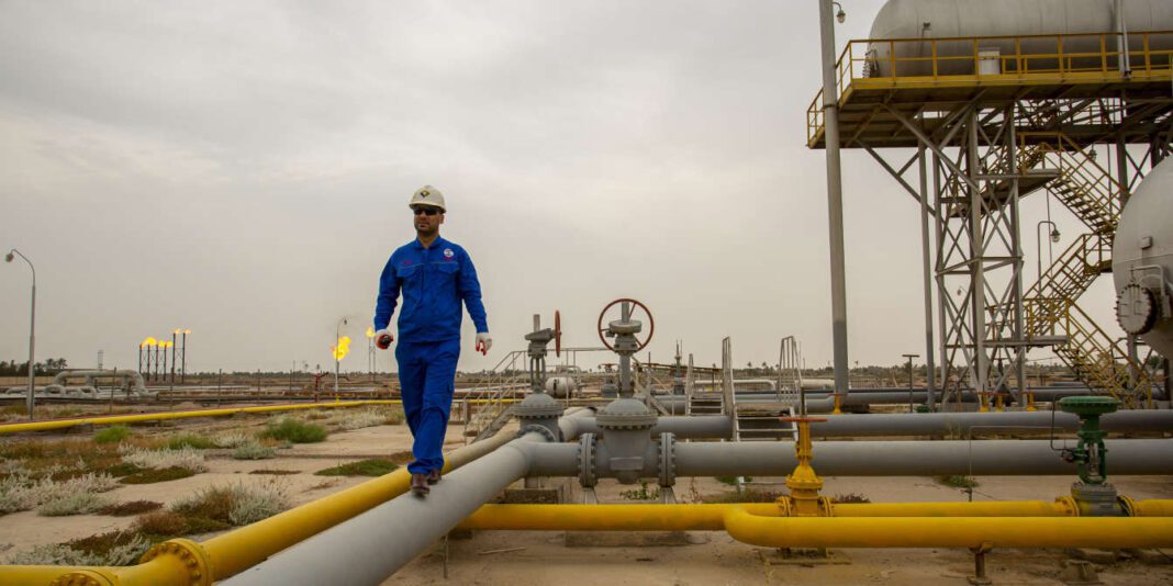 Ingénieur en combinaison bleue sur plateforme pétrolière en plein air.