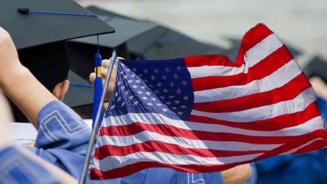 Étudiants en graduation tenant un drapeau américain.