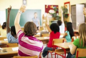 Enfants en classe levant la main lors d'une activité scolaire.