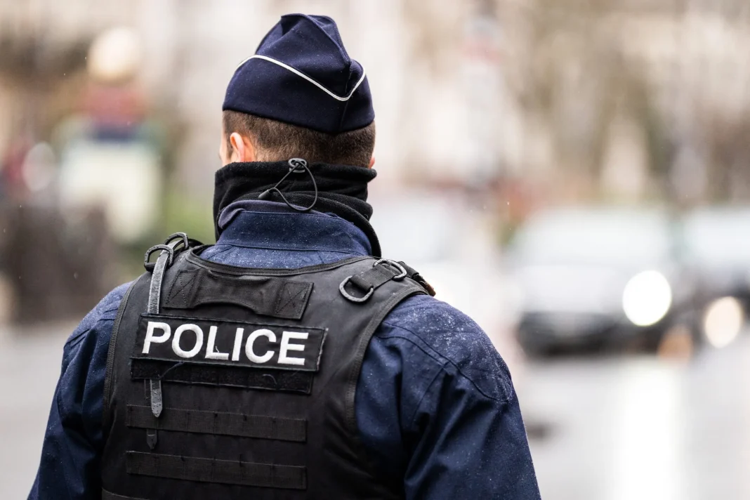 Policier en uniforme dans une rue urbaine, vue de dos.