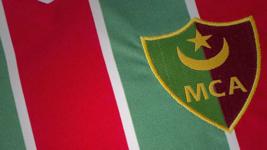 Logo du Mouloudia d’Alger sur le maillot vert et rouge.
