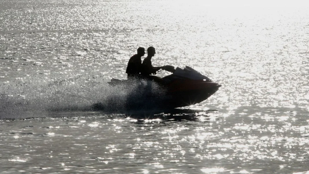 Deux jeunes sur un jet ski naviguant sur la mer au coucher du soleil.