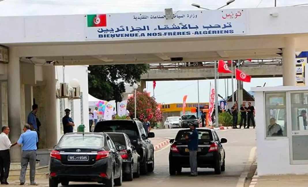 Point de passage frontalier Tunisie-Algérie avec drapeaux et véhicules.