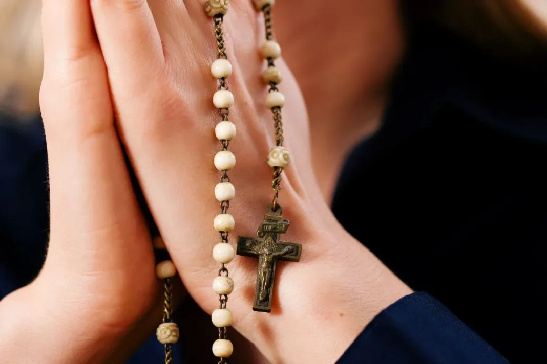 Personne priant avec un chapelet lors d'une cérémonie religieuse.