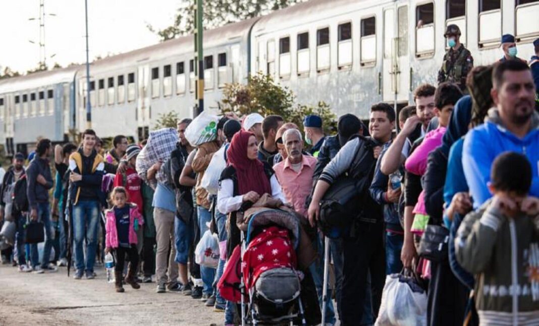 Groupe de migrants faisant la queue près d'un train en France.