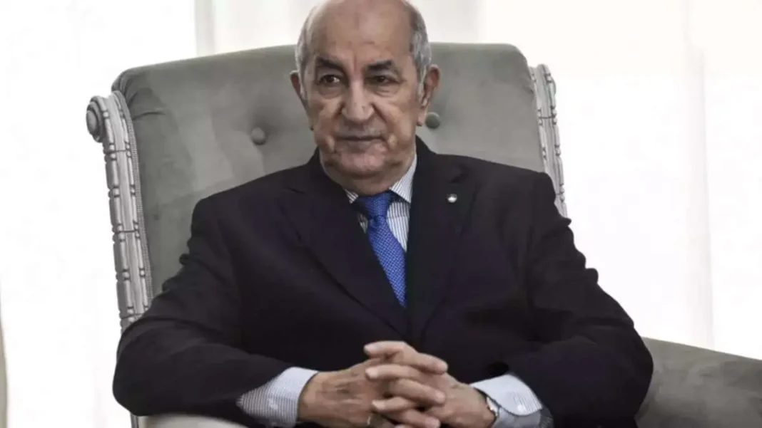 Homme politique en réunion, portant costume noir et cravate bleue.