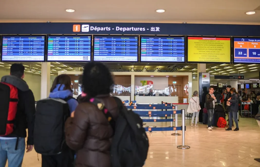 Tableau d'affichage des départs à l'aéroport avec voyageurs.