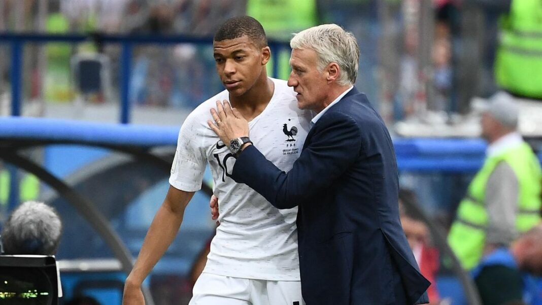 Deschamps parle à Mbappé lors d'un match de football.