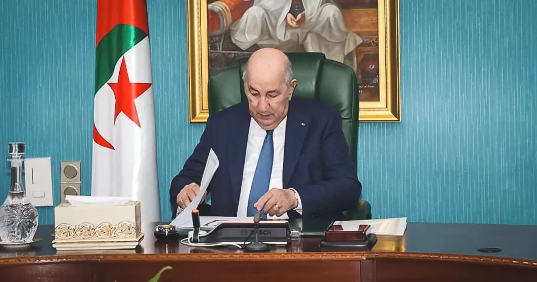 Abdelmadjid Tebboune à son bureau avec drapeau algérien en arrière-plan.