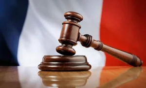 Gavel de juge en bois avec drapeau français en arrière-plan.