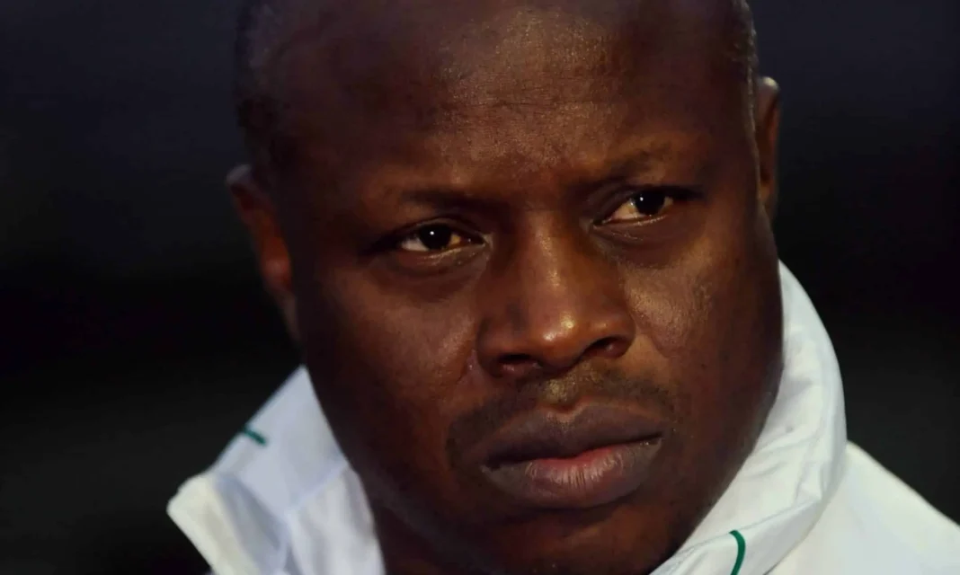 Homme sénégalais concentré, regard sérieux, portant une veste blanche.