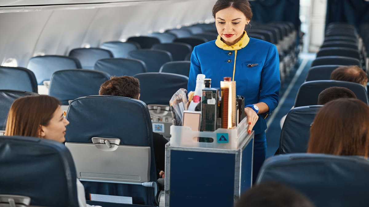 Hôtesse de l'air servant des boissons à bord d'un avion.