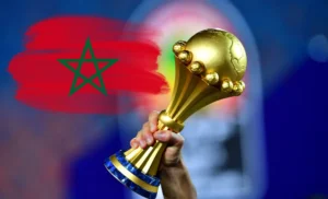 Main tenant la coupe d'Afrique avec drapeau du Maroc en arrière-plan.