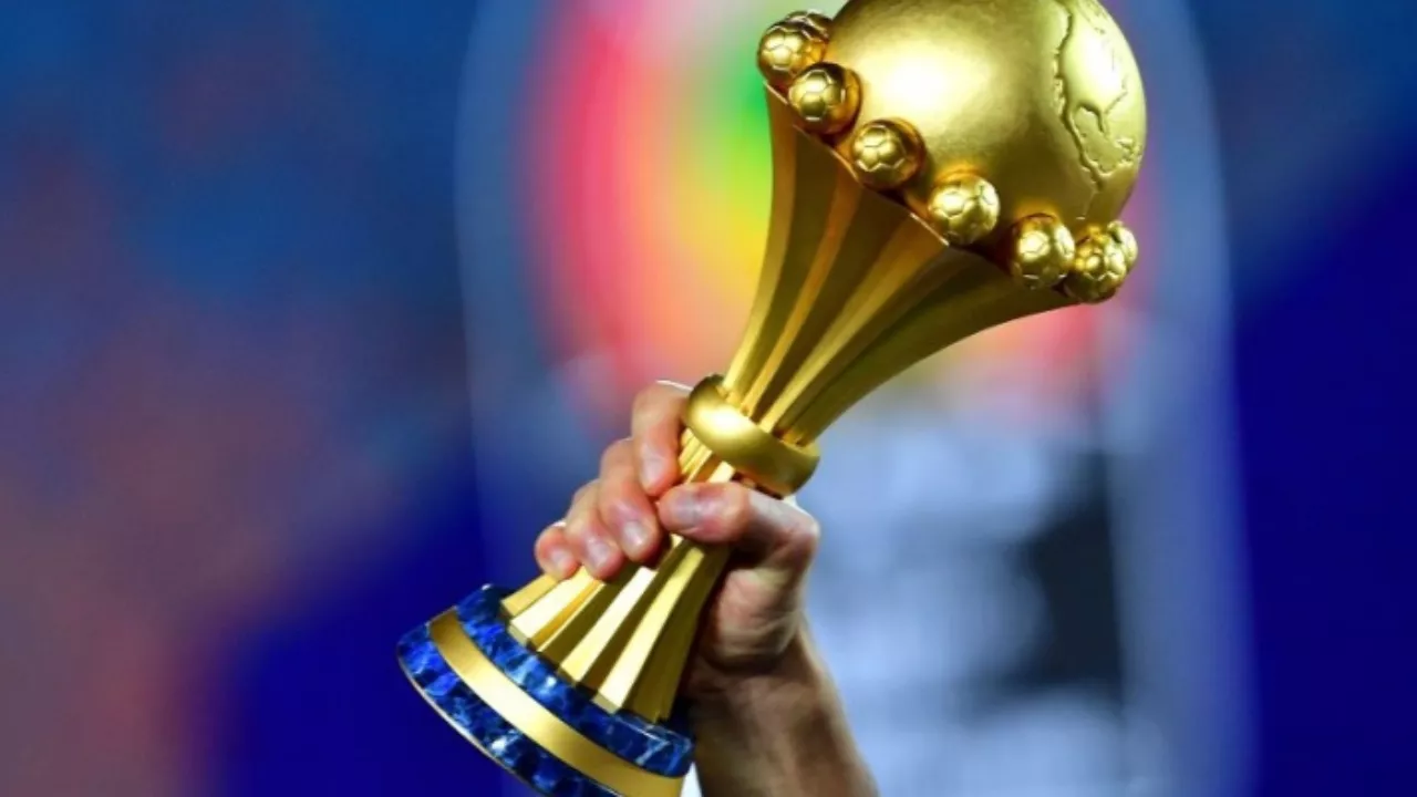 Main tenant un trophée de football de la CAN 2024.