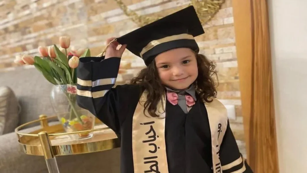 Jeune fille en robe de graduation souriante et tenant son chapeau de diplômée.