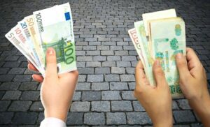 Deux mains tenant des billets de banque en euros et dinars algériens.