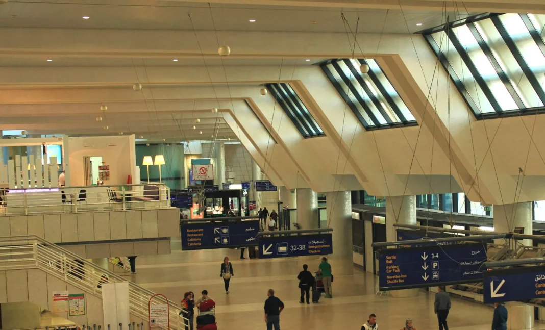 Vue intérieure de l'aéroport d'Alger avec zones d'attente et panneaux d'information.