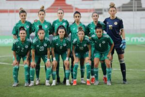 Groupe de joueuses de football algériennes en uniforme vert sur le terrain.