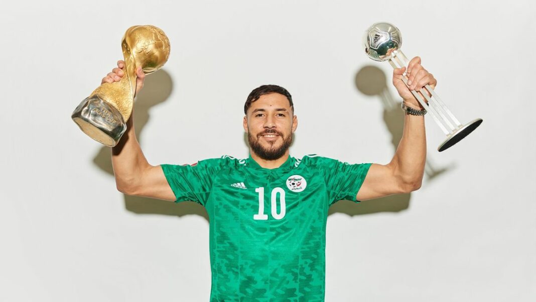 Belaïli célèbre sa victoire avec deux trophées de football.