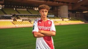 Jeune footballeur en tenue de match dans un stade vide.
