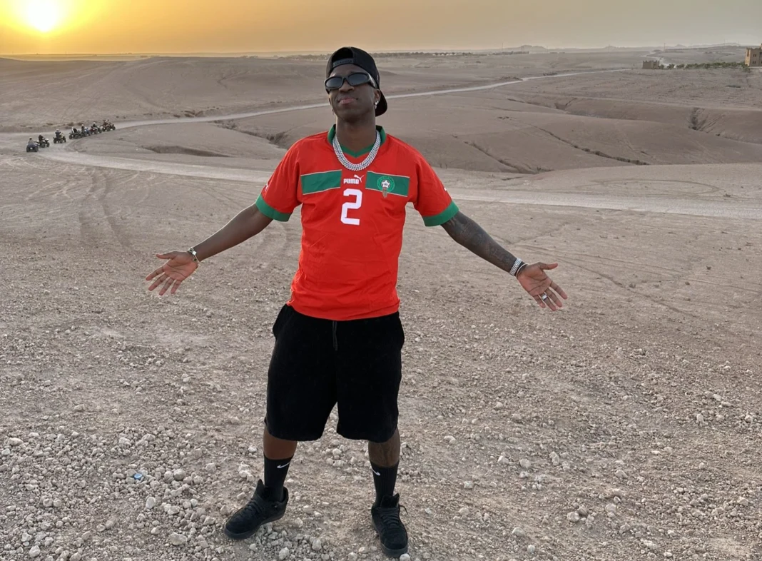 Jeune homme portant un maillot de football dans un désert au coucher du soleil.