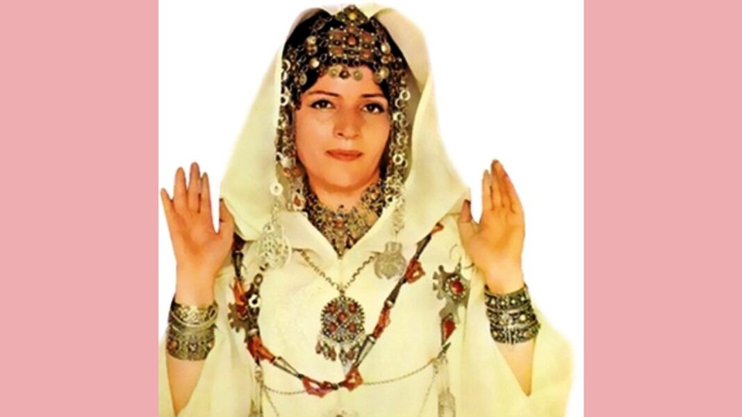 Femme en costume traditionnel maghrébin avec bijoux et voile blanc.