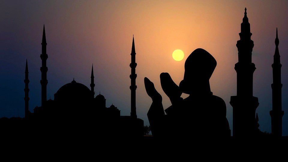 Silhouette d'une mosquée avec minarets au coucher du soleil.