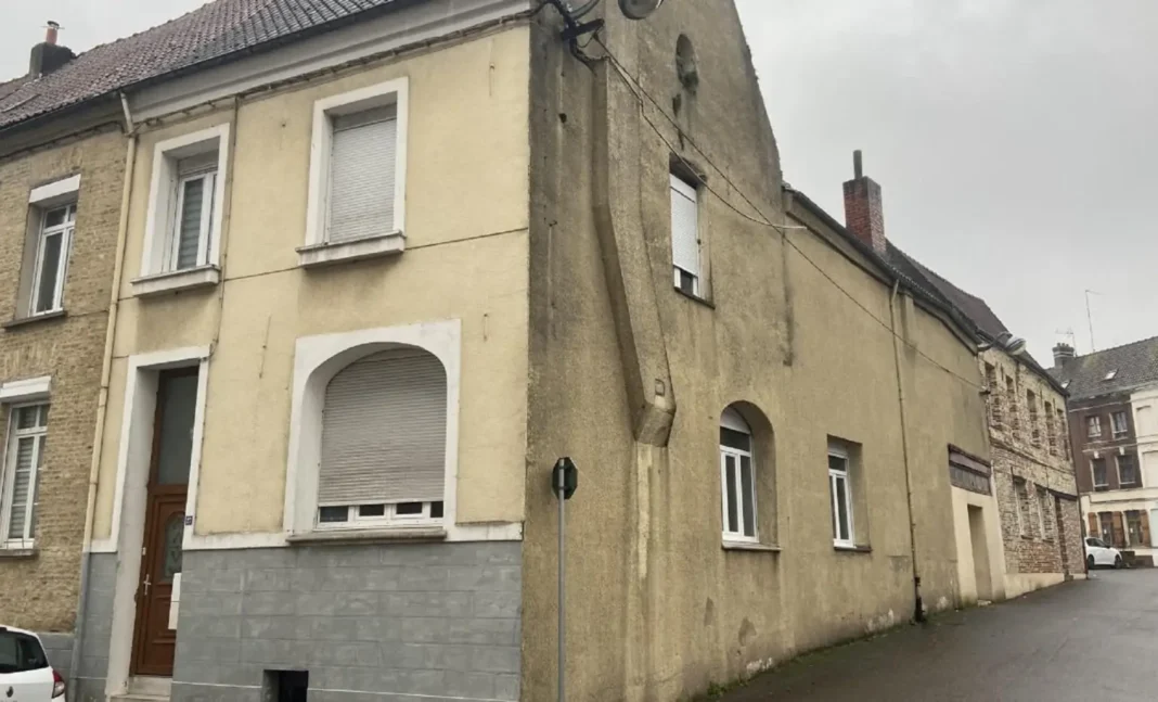 Façade d'une maison ancienne en France avec murs jaunis et fenêtres.